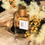 Ingenious Ginger perfume bottle with golden cap surrounded by yellow flowers and berries on natural wood background