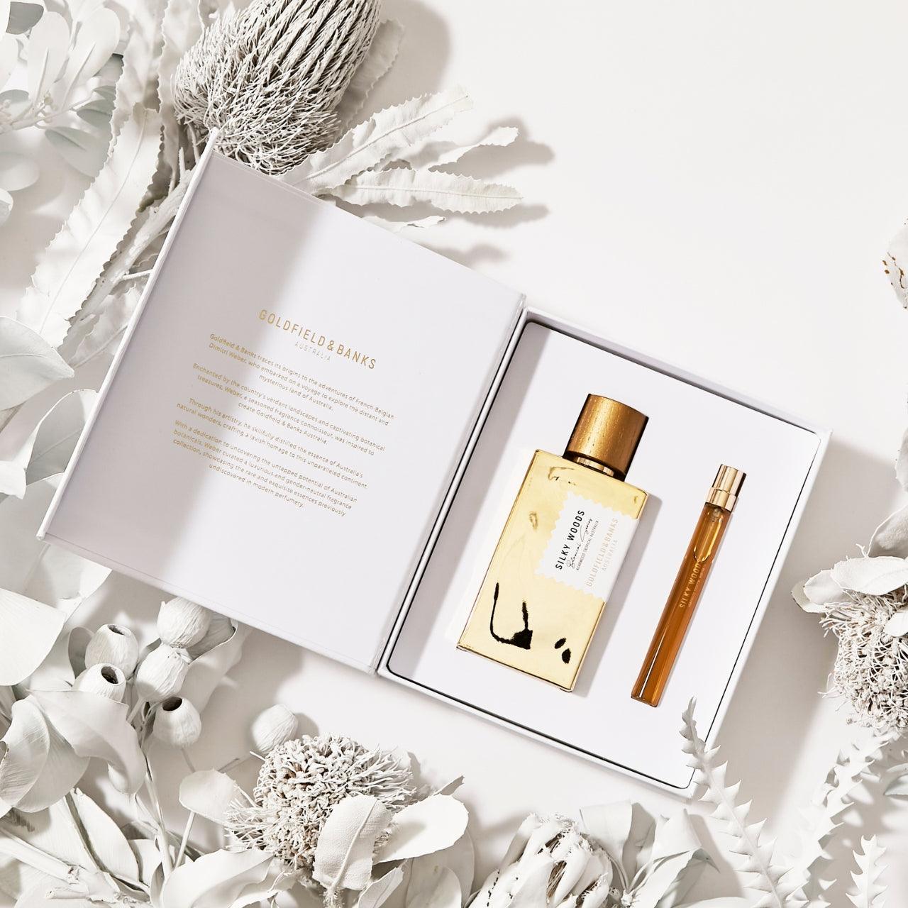 Silky Woods Holiday Gift Set with 100ml gold bottle and 10ml travel spray in open white box surrounded by white dried flowers